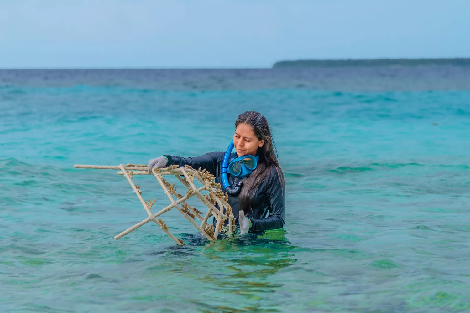 A woman working on a Reefscapers coral frame underwater.
