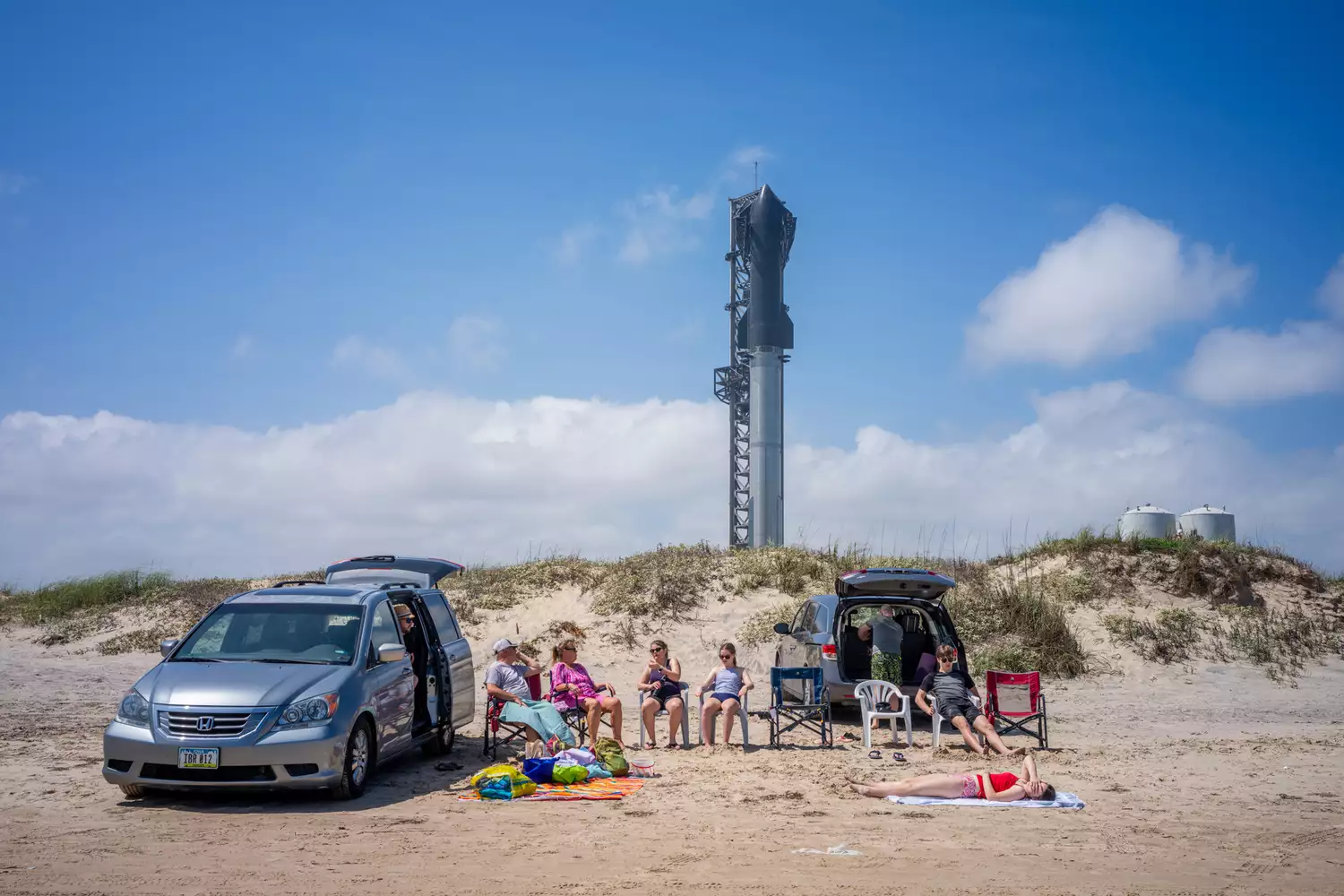 Beachgoers relax on the sand near the massive SpaceX Starship rocket at the Starbase facility in Boca Chica.