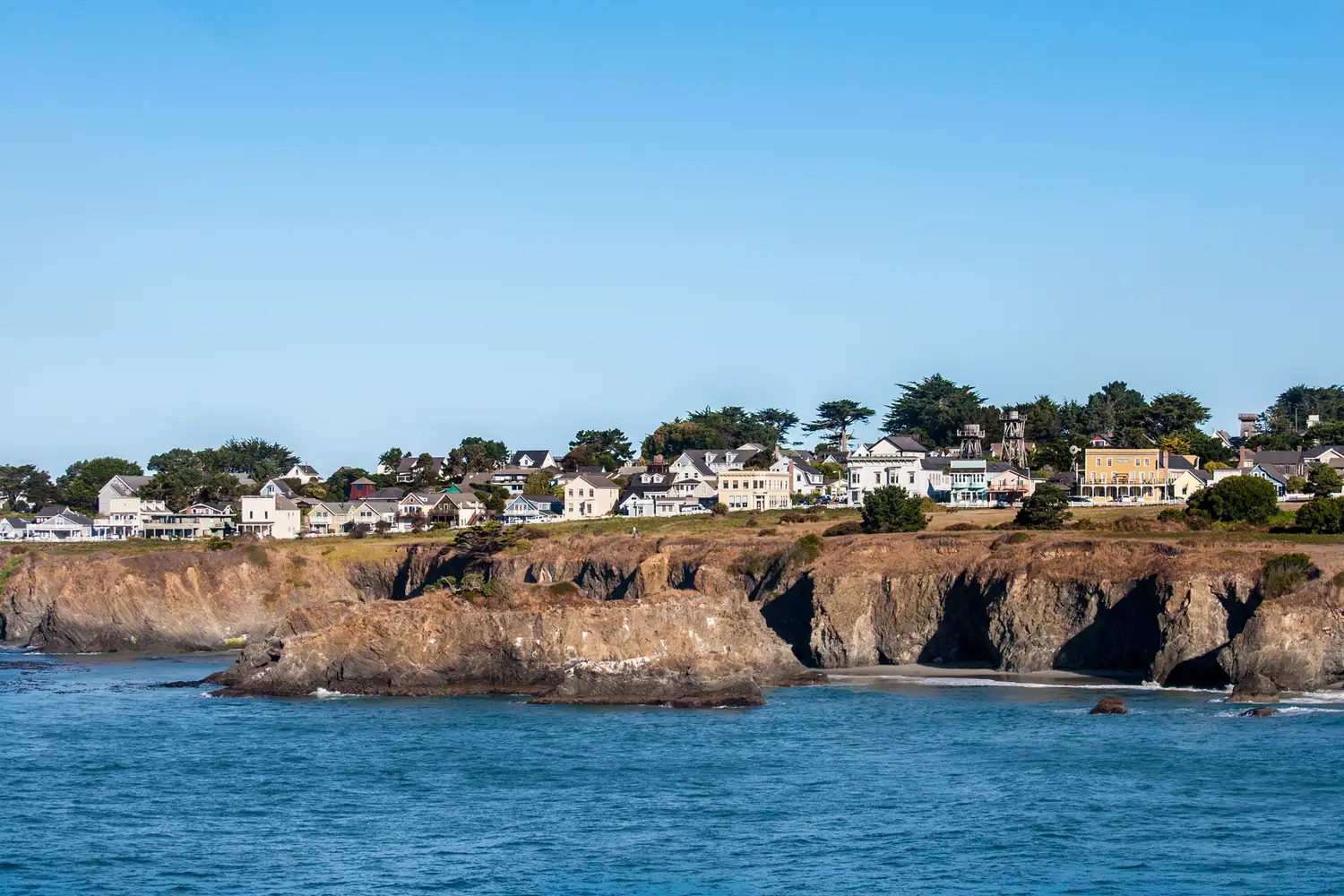 Cliffs and houses overlooking the blue Pacific Ocean in Mendocino, California.