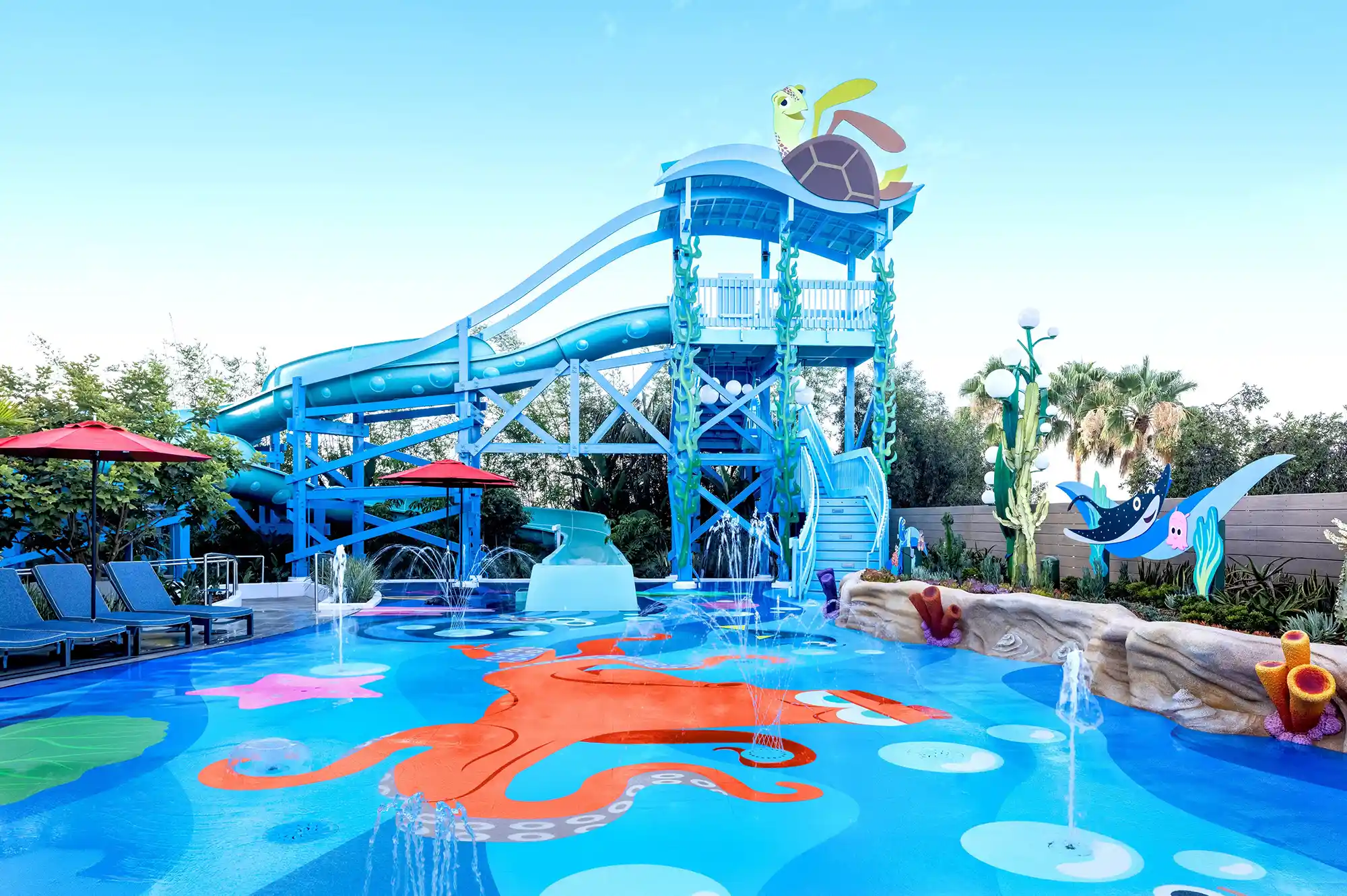 The Nemo's Cove splash pad area at Pixar Place Hotel featuring colorful water slides and character graphics.