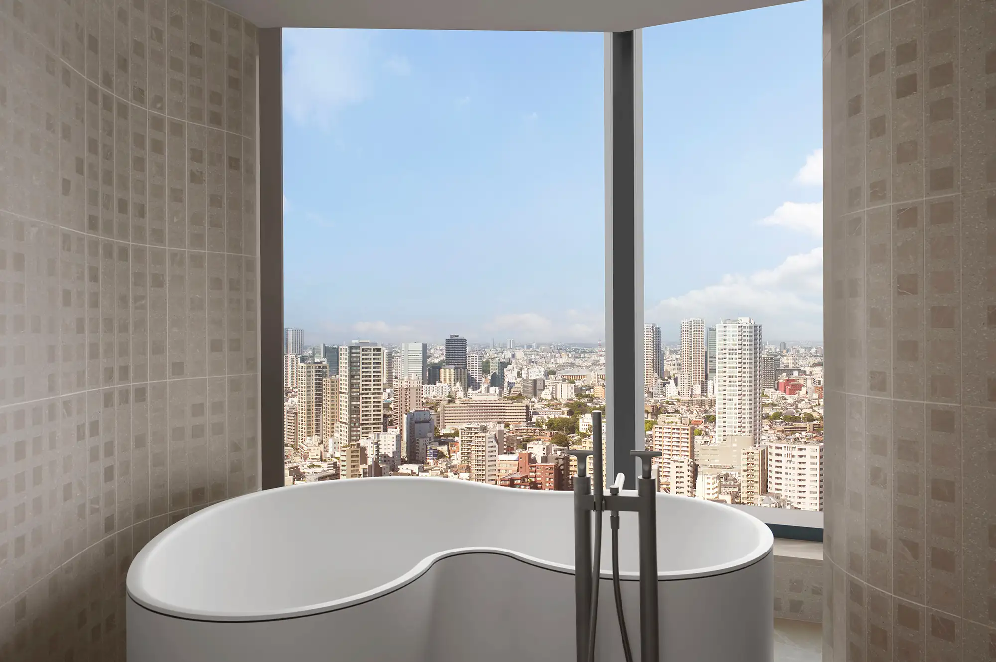 A deep soaking tub placed next to a large window with views of the Tokyo cityscape.