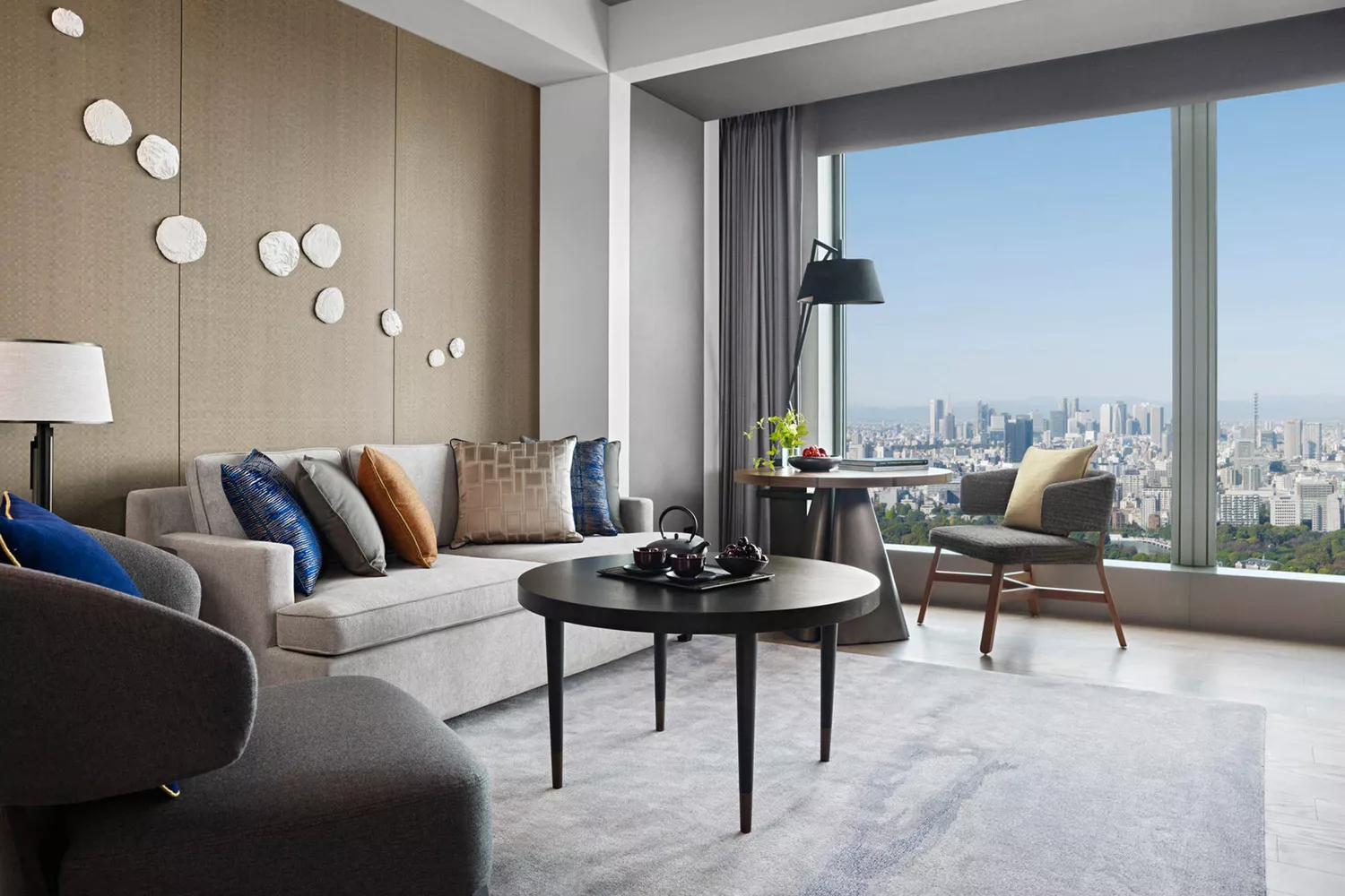 Living area of a suite at Four Seasons Otemachi overlooking the Tokyo skyline and Imperial Palace gardens.