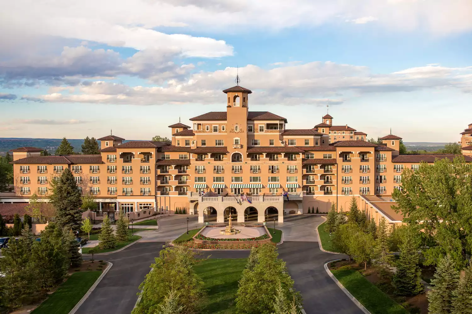 The historic exterior of The Broadmoor resort under a golden sunset sky.