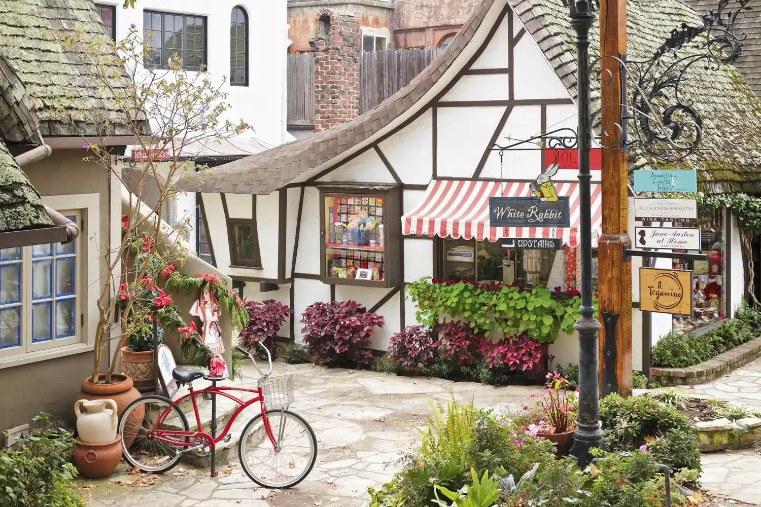 A red cottage-style storefront in Carmel-by-the-Sea with a bicycle parked outside.