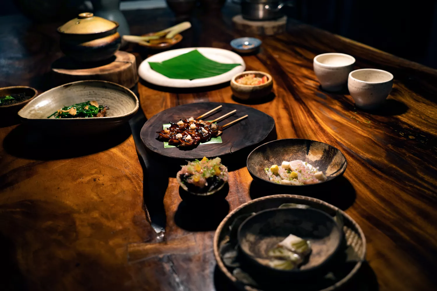 Artfully plated Filipino dishes on a rustic dark wooden table at Toyo Eatery.
