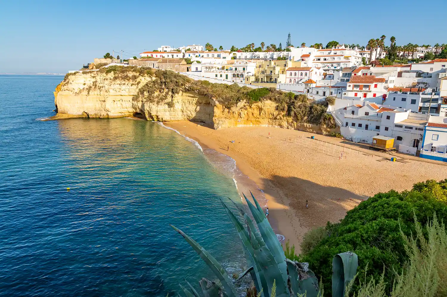 The village of Carvoeiro with its white buildings nestled on a cliff overlooking a beach.
