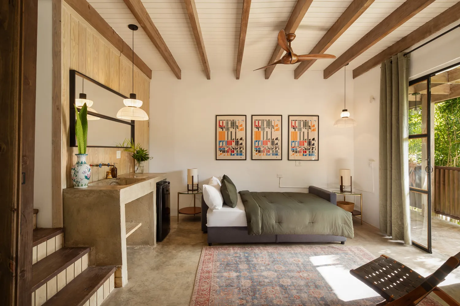 A modern minimalist hotel room with wood accents and a sliding glass door opening to a garden.