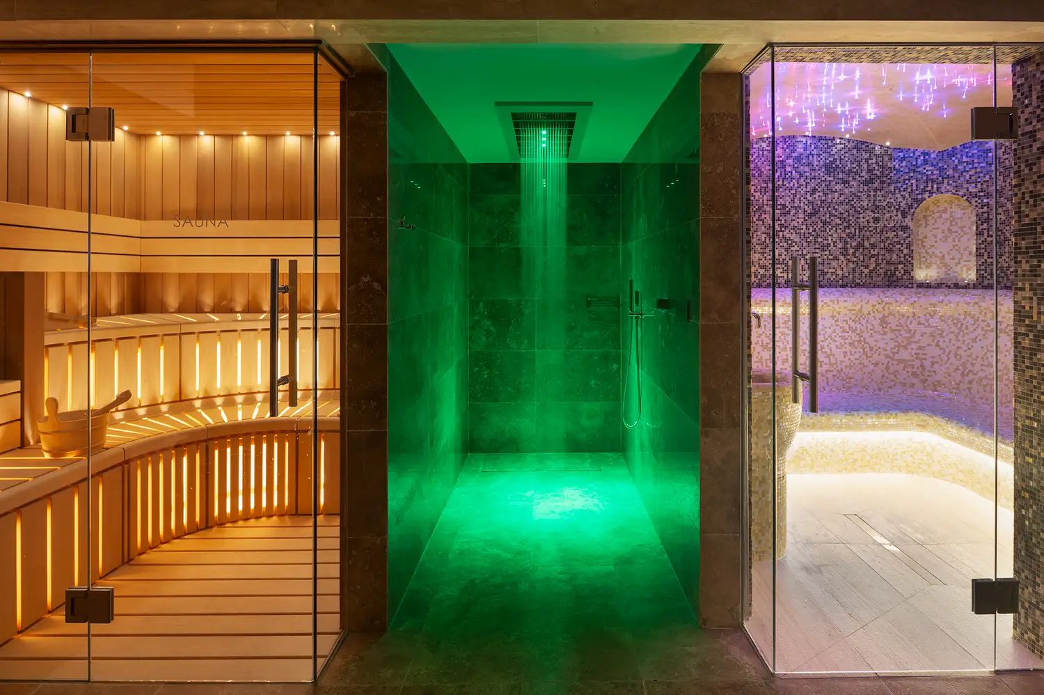 An ultra-modern spa interior with an indoor pool, therapeutic green lighting, and a dry sauna.