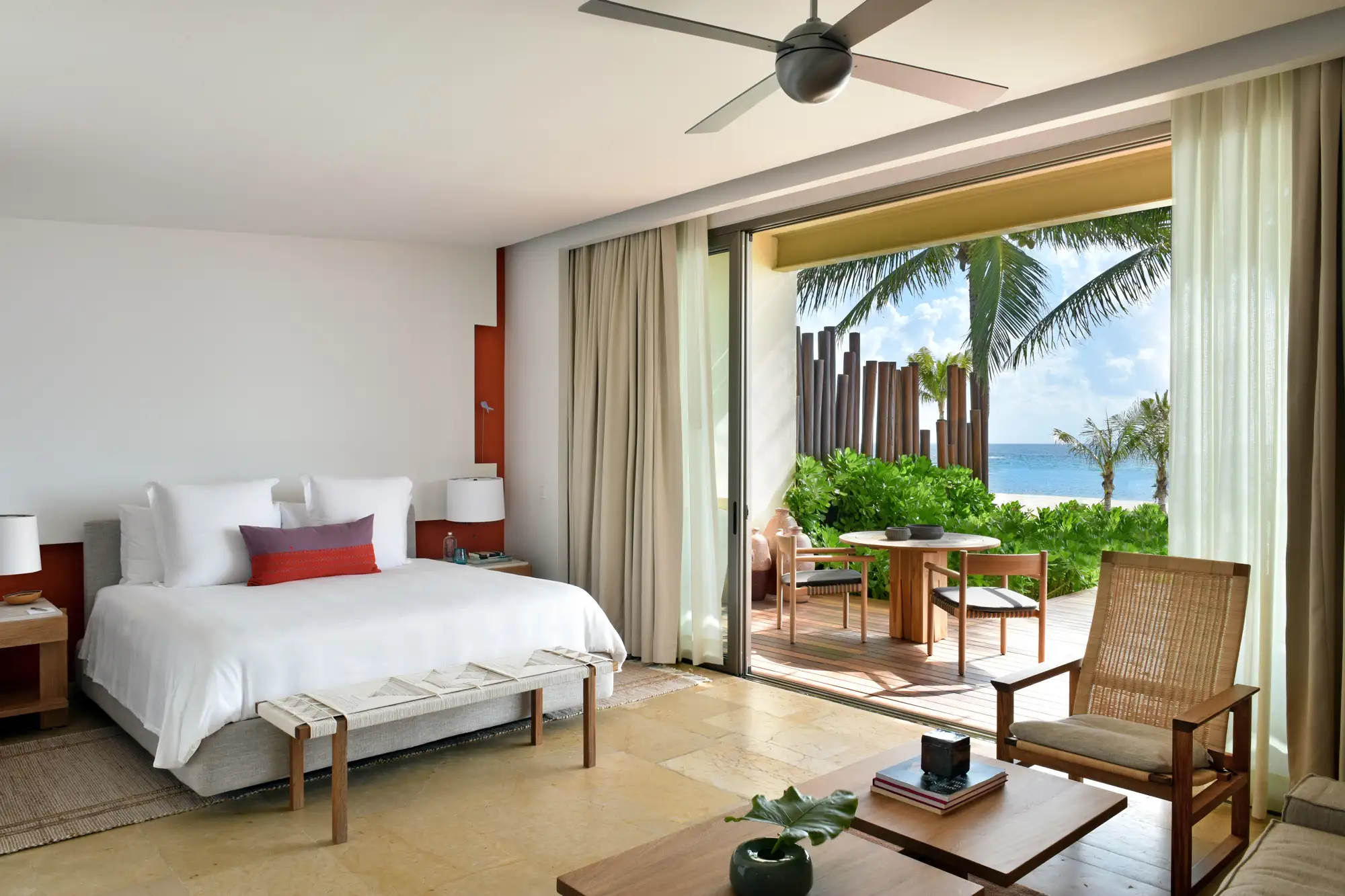 Interior of a beachfront studio suite with views of the sand and ocean through floor-to-ceiling windows.