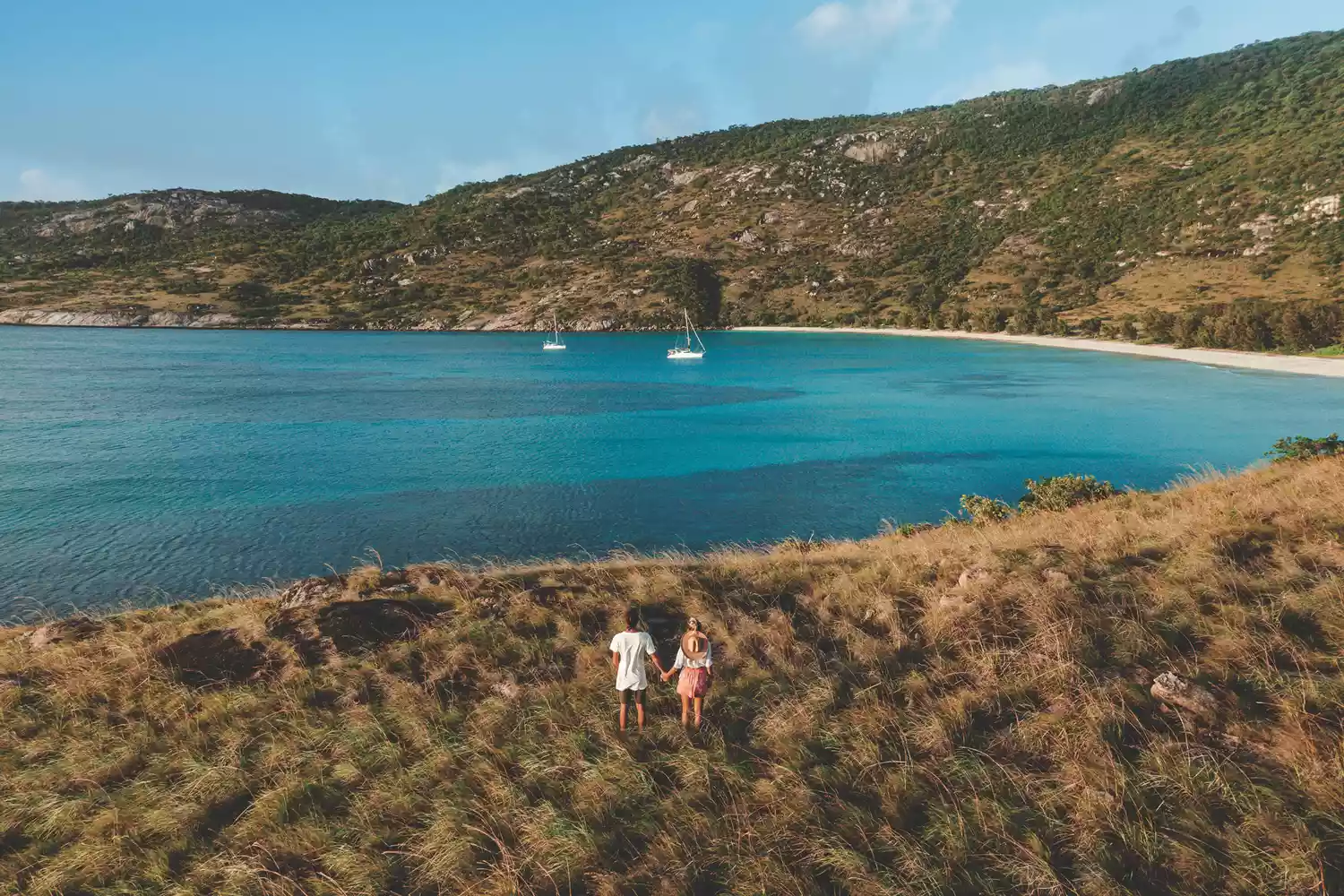 A couple standing on the shore of a tropical island in the Great Barrier Reef region.
