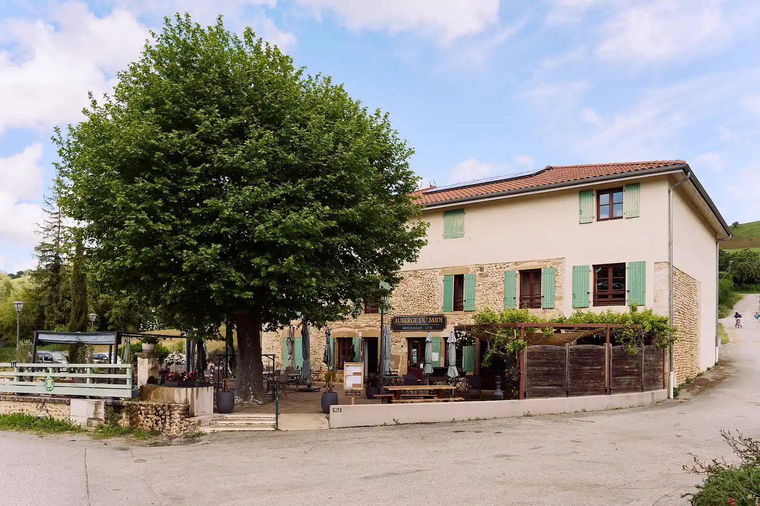 The rustic stone exterior of Auberge du Midi with its charming shutters and outdoor seating area.