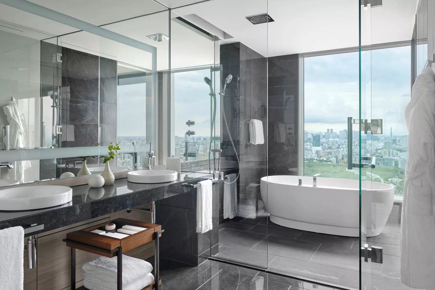 Luxury bathroom in a suite featuring a deep soaking tub positioned next to a window with Tokyo city views.