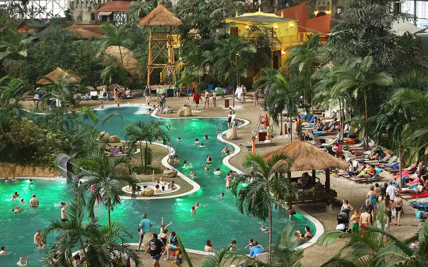 High-angle view of the internal waterpark structures, slides, and lounging areas inside the massive hanger.