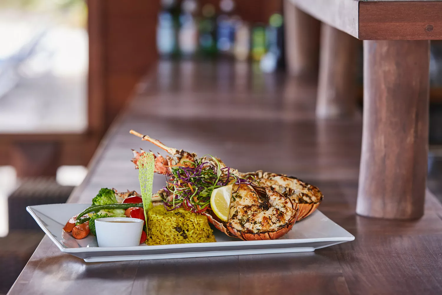 A prepared plate featuring a whole grilled Anegada spiny lobster.
