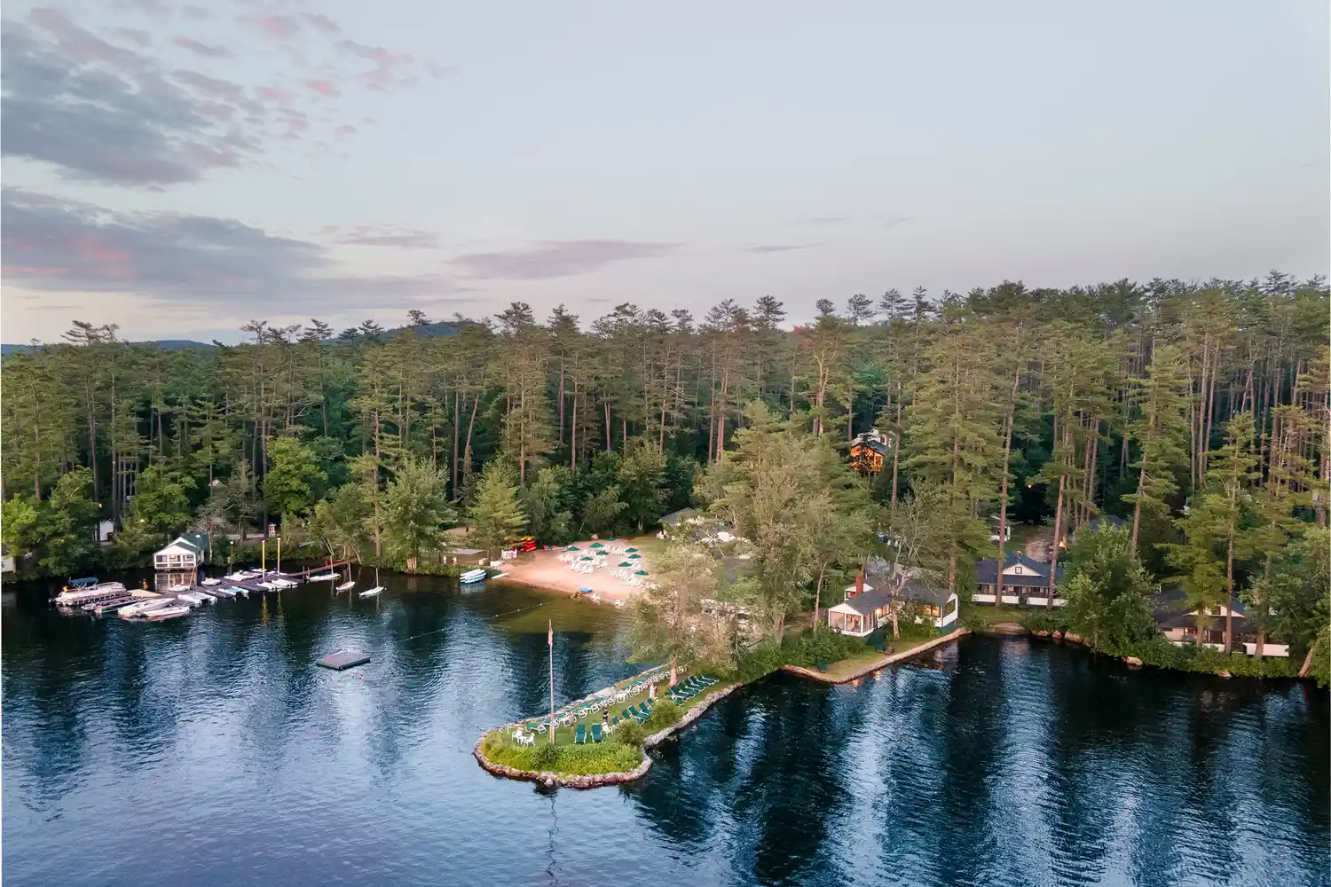 A scenic aerial view of Quisisana Resort surrounded by Lake Kezar and dense forest in Maine.