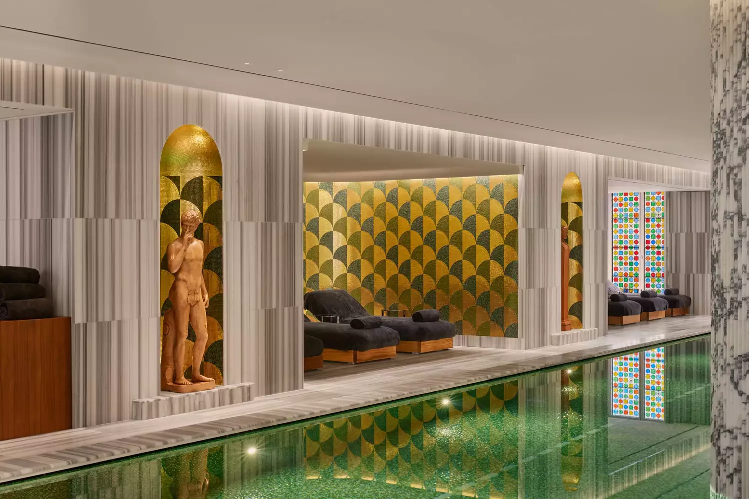 Luxury indoor spa pool at Bulgari Hotel Roma with gold accents, marble, and a Roman statue.