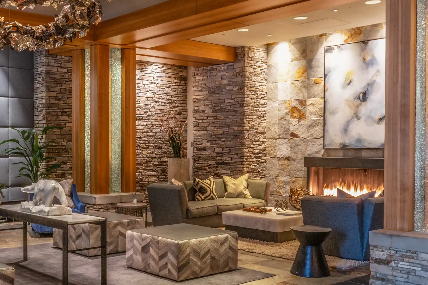 A luxury lounge area with a lit stone fireplace and modern furniture at the Four Seasons Resort & Residences Whistler.
