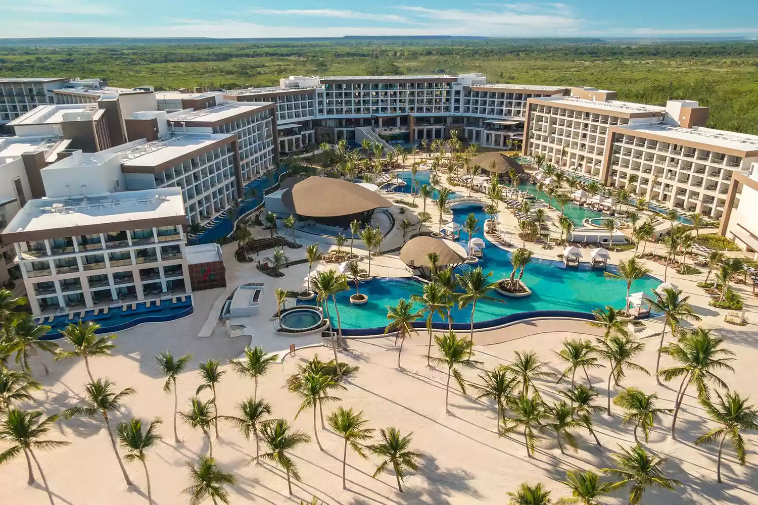 Modern architecture of Hyatt Ziva Cap Cana resort with expansive swimming pools overlooking the blue ocean.