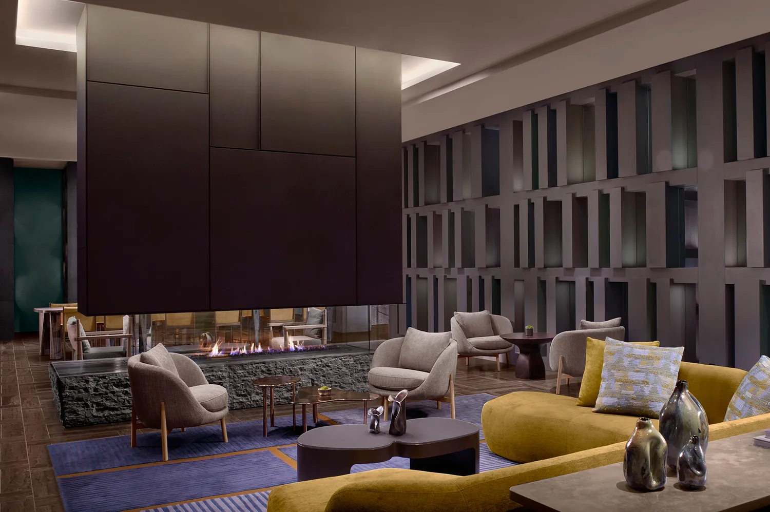 Modern hotel lounge with a sleek central fireplace and minimalist seating.