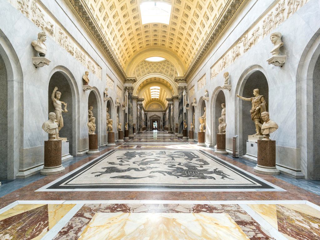 The ornate Gallery of Maps with frescoed ceilings and crowded corridors in the Vatican Museums.