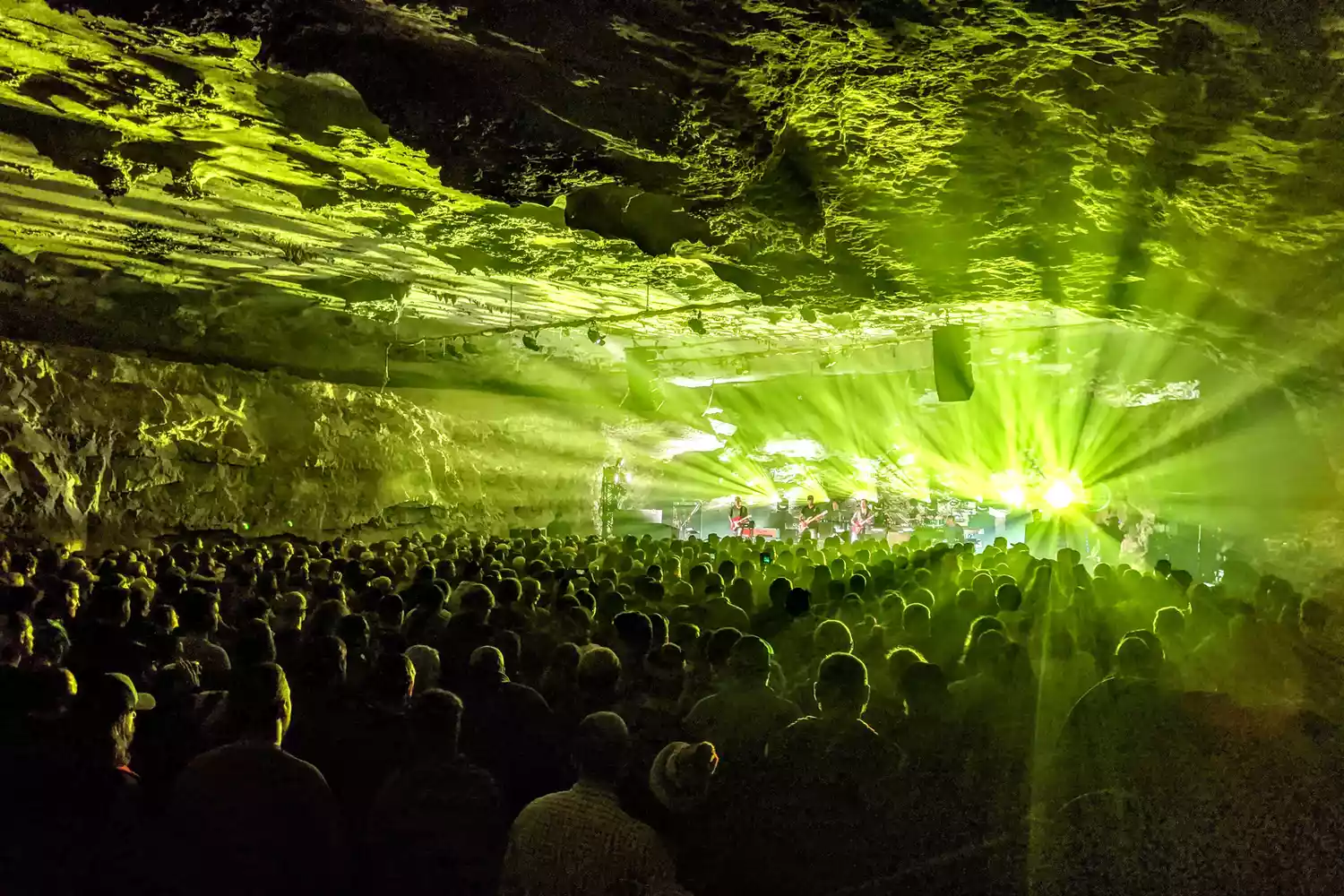 A live concert being performed inside a large, naturally illuminated cave.
