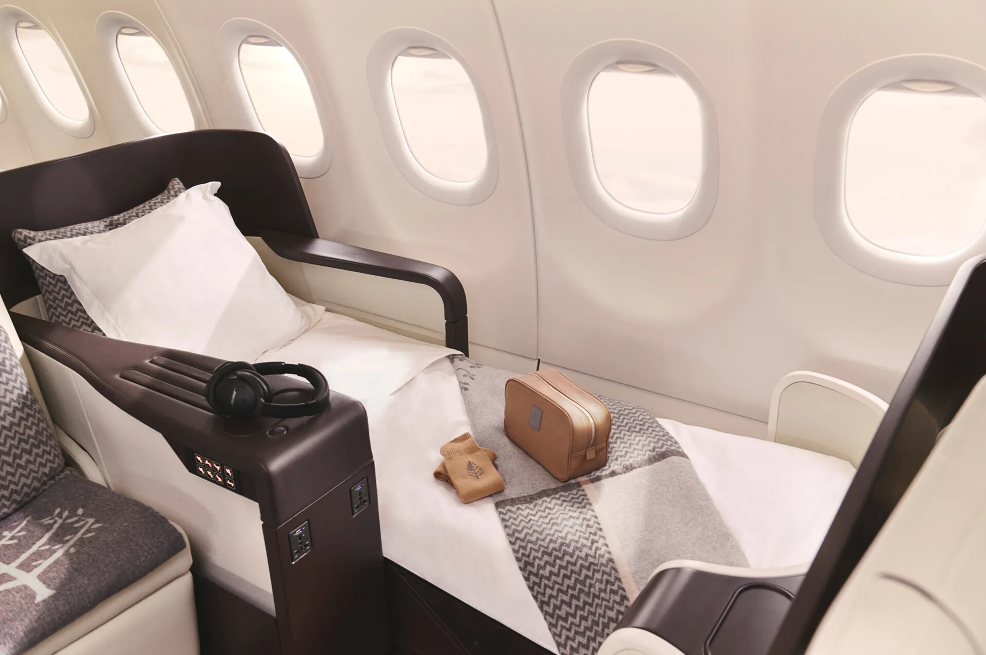 A 180-degree lie-flat aircraft seat with a plush blanket and pillow.