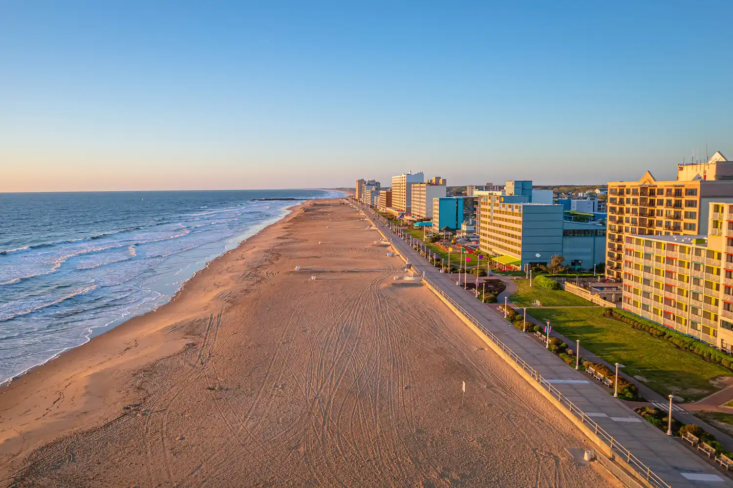 Aerial perspective of the Virginia Beach coastline showing the boardwalk and high-rise buildings.