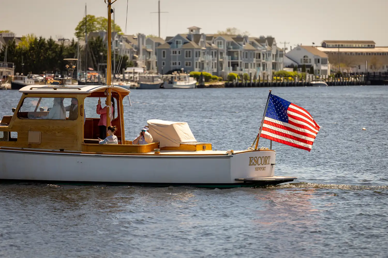 A charter motorboat with an American flag cruising in front of the Mystic coastline.