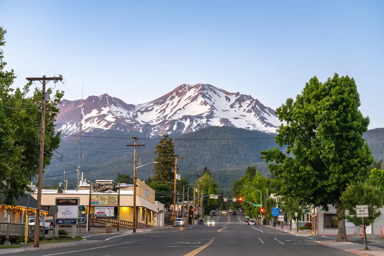 A view of the snow-capped Mount Shasta towering over a small town street.