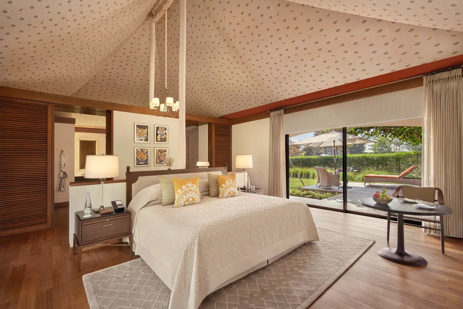 Large bedroom suite with elegant decor and floor-to-ceiling windows showing a private garden.