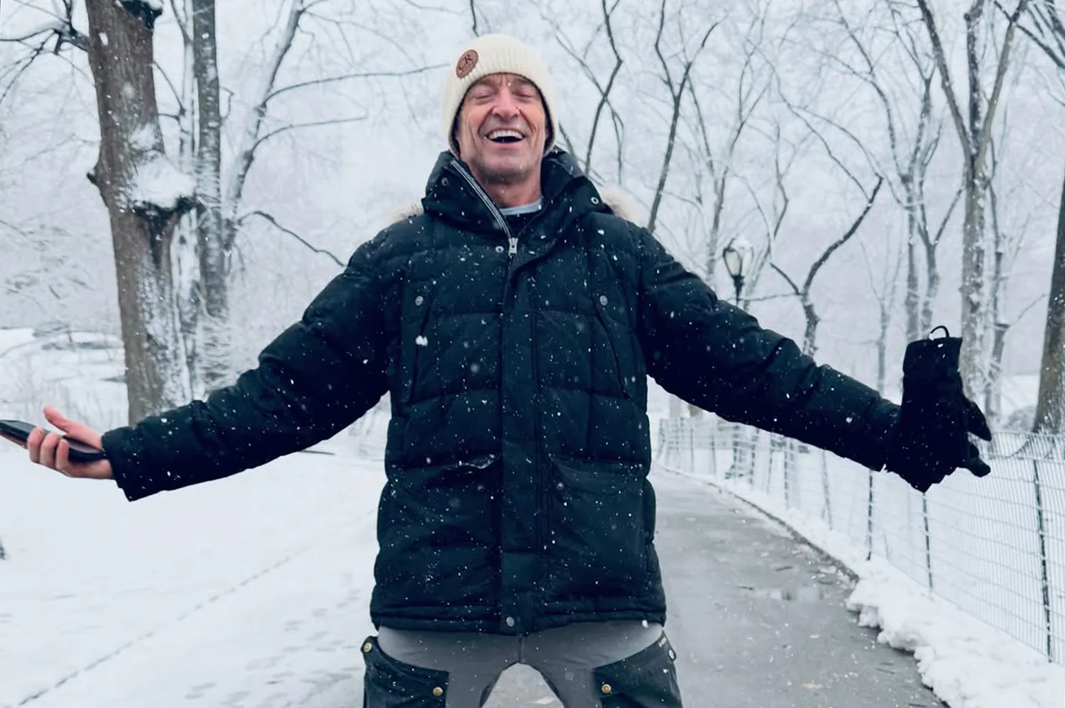 Hugh Jackman enjoying the snowy weather in an urban park setting.