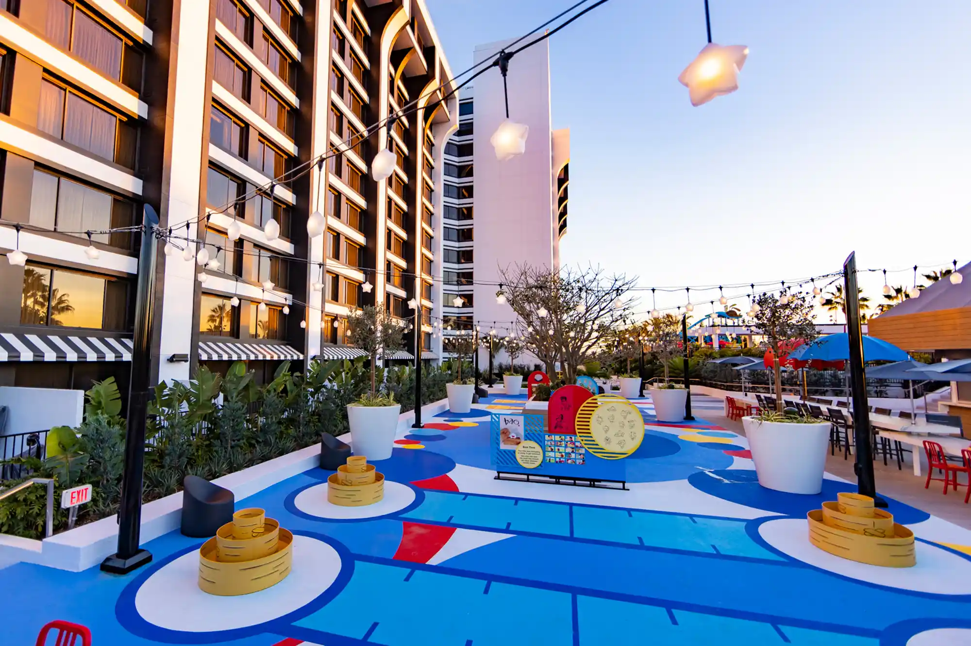 An outdoor courtyard and recreation deck at Pixar Place Hotel with string lights and family activities.