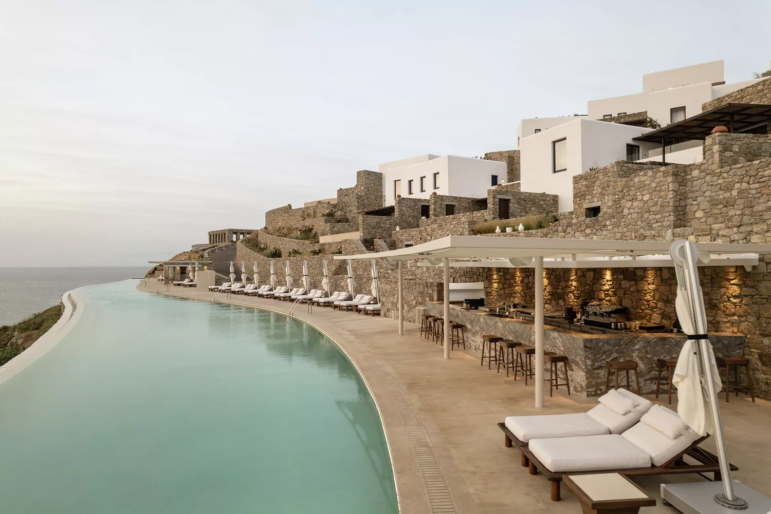 Long saltwater infinity pool at Cali Mykonos overlooking the ocean.