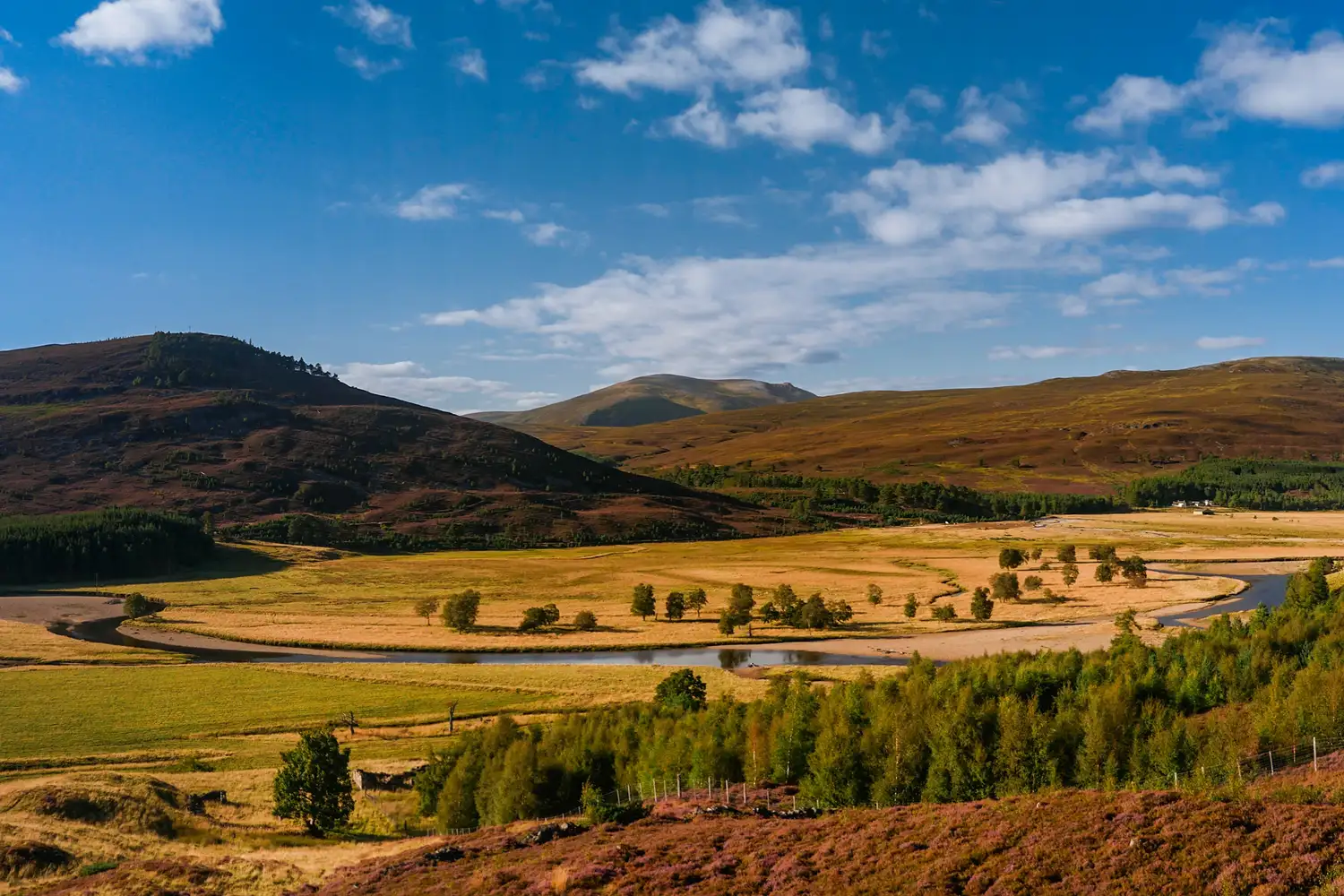 The autumn landscape of Braemar showing rolling hills and a winding river.