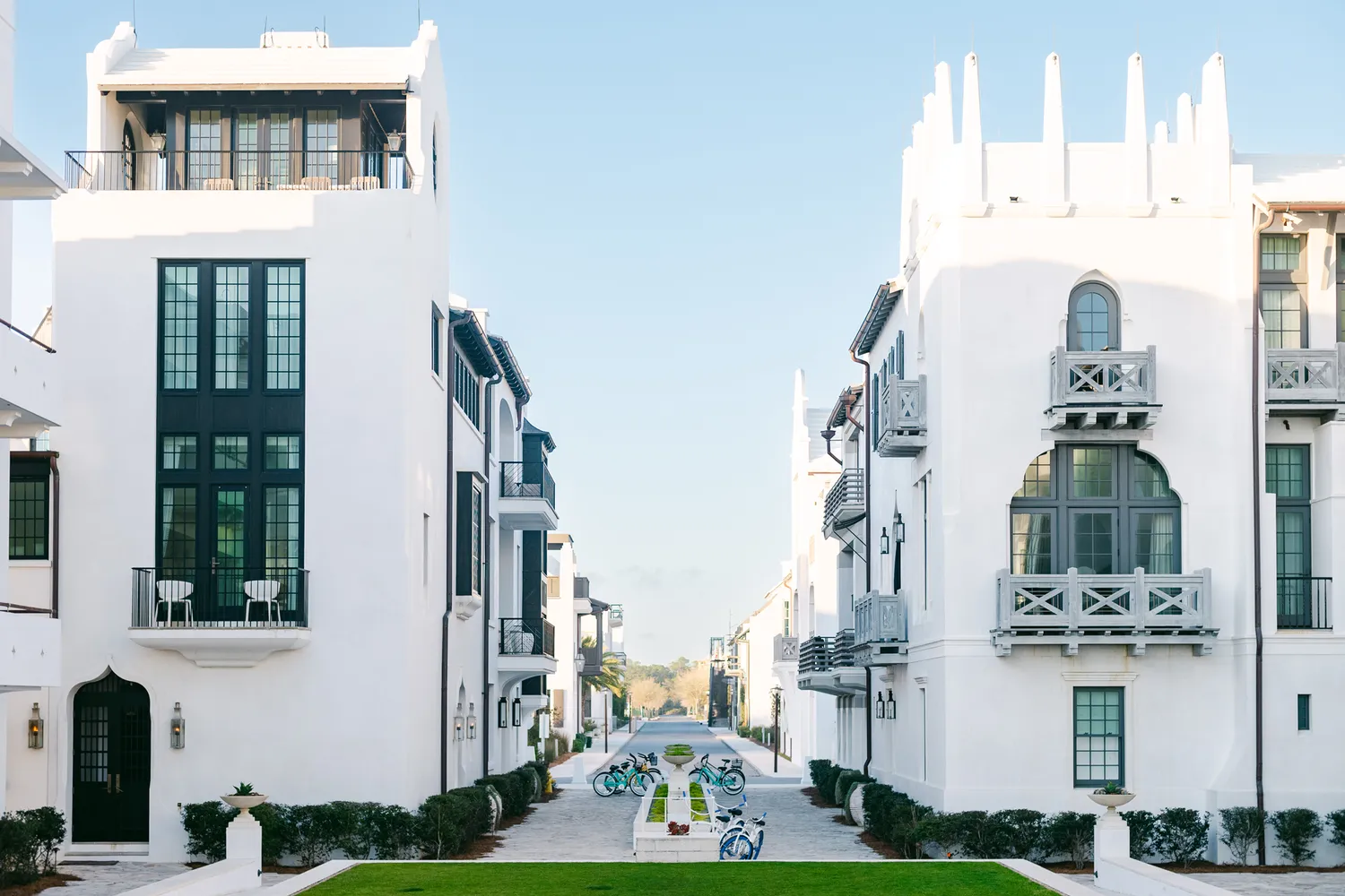 A scenic urban view of a promenade lined with white residential buildings and parked bikes in Alys Beach, Florida.
