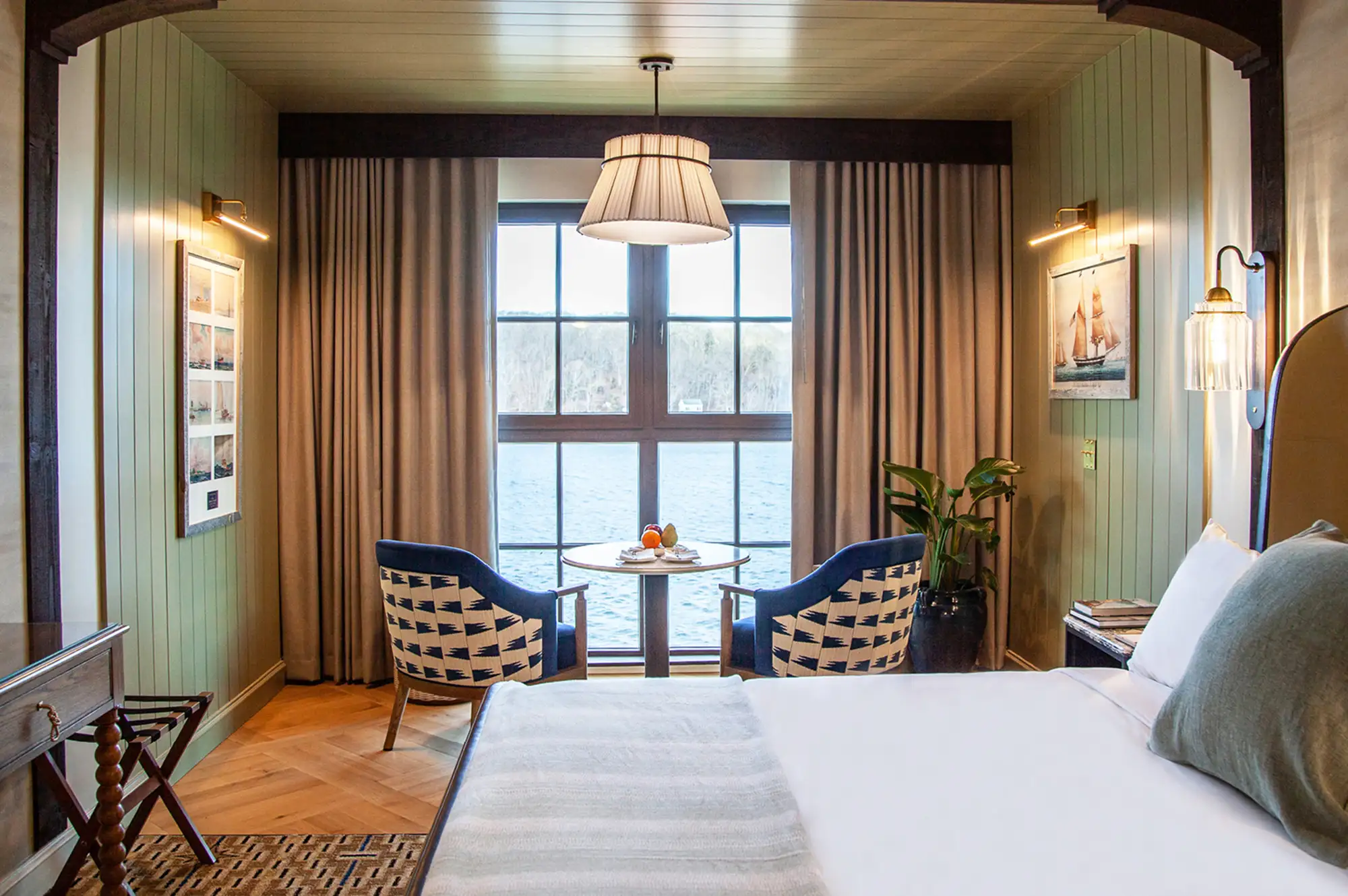 A luxury hotel room with blue and white decor and a window overlooking the Mystic waterfront.