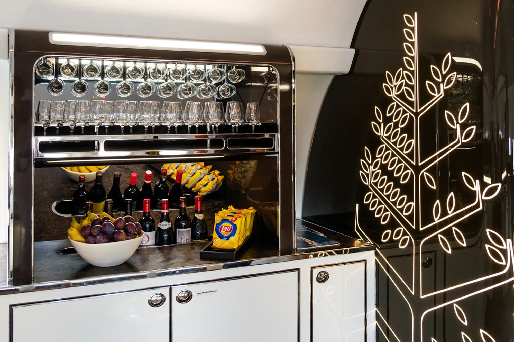 A close-up of a private jet refreshment area with wine, fresh fruit, and premium snacks.