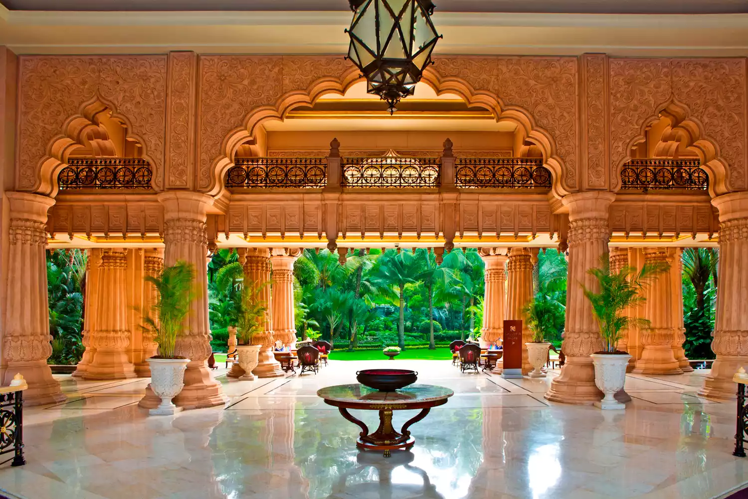 The grand, double-height lobby of The Leela Palace Bengaluru featuring ornate columns and gold leafing.