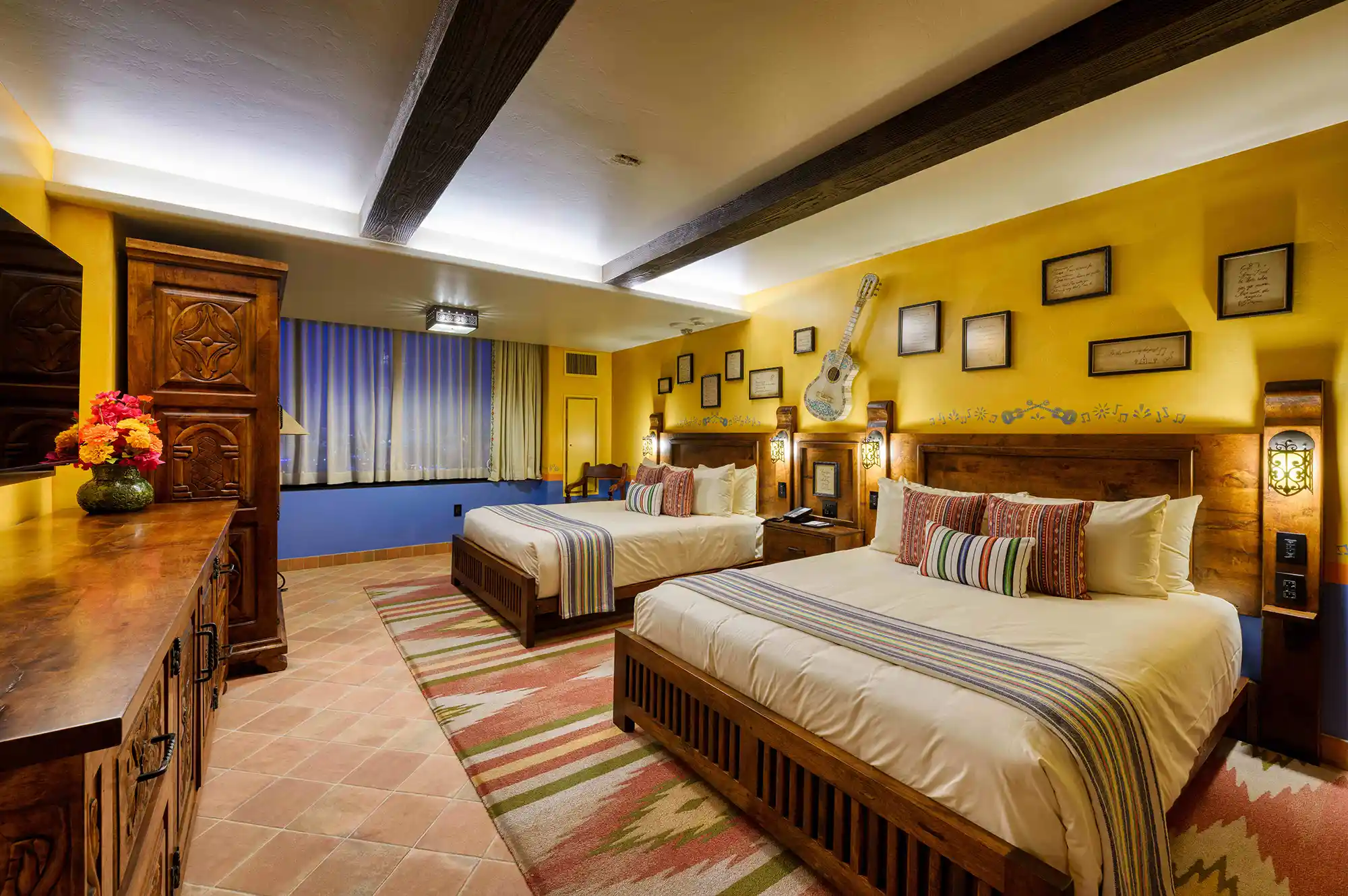 A family suite bedroom at Pixar Place Hotel decorated with colorful Coco film-themed headboards and patterns.