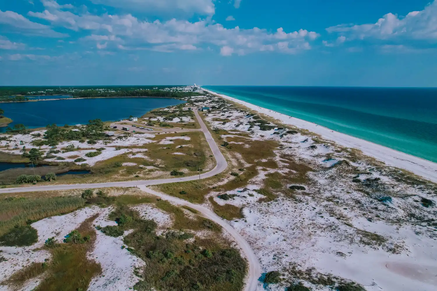 Aerial view of a road winding through sand dunes and coastal water in Grayton Beach State Park.