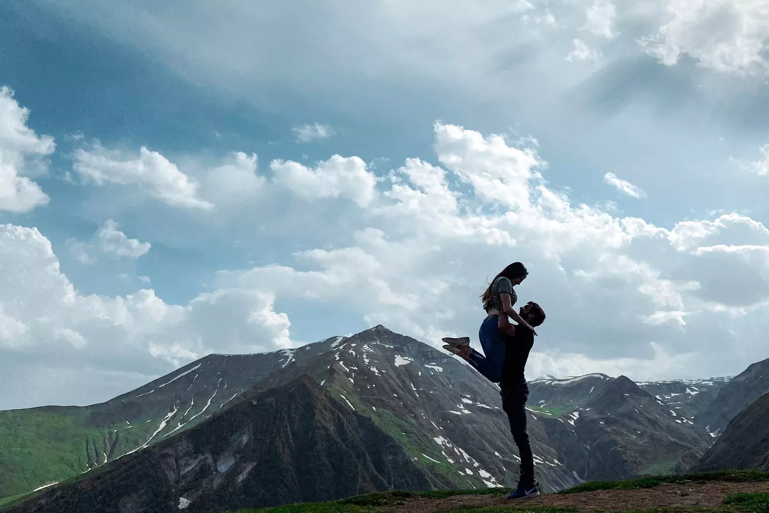 A man lifting a woman in a 'dirty dancing' style pose against a Tbilisi city backdrop.