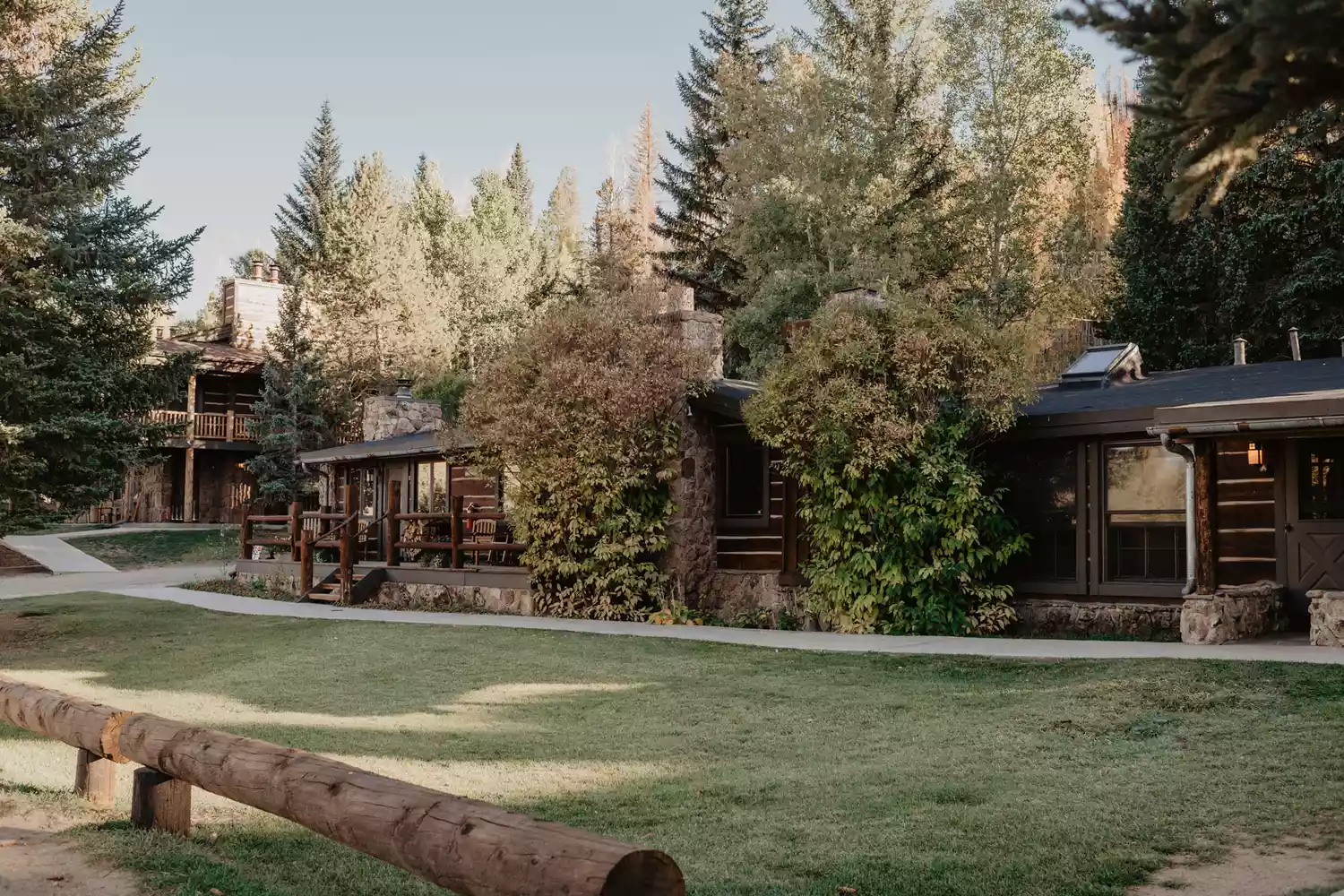 Wooden cabins at C Lazy U Ranch set against a mountain backdrop.