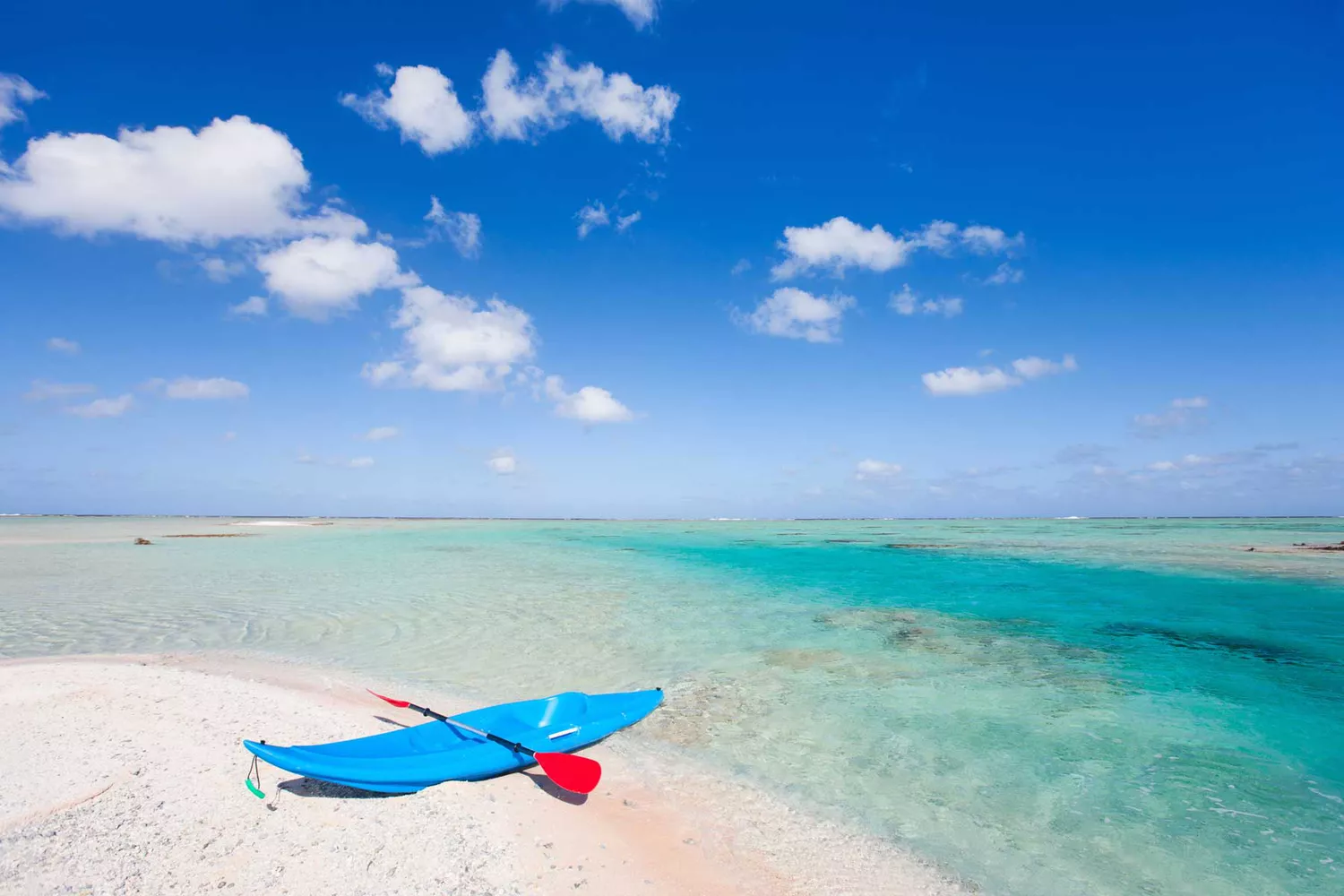A yellow kayak resting on a pink sand beach in French Polynesia.