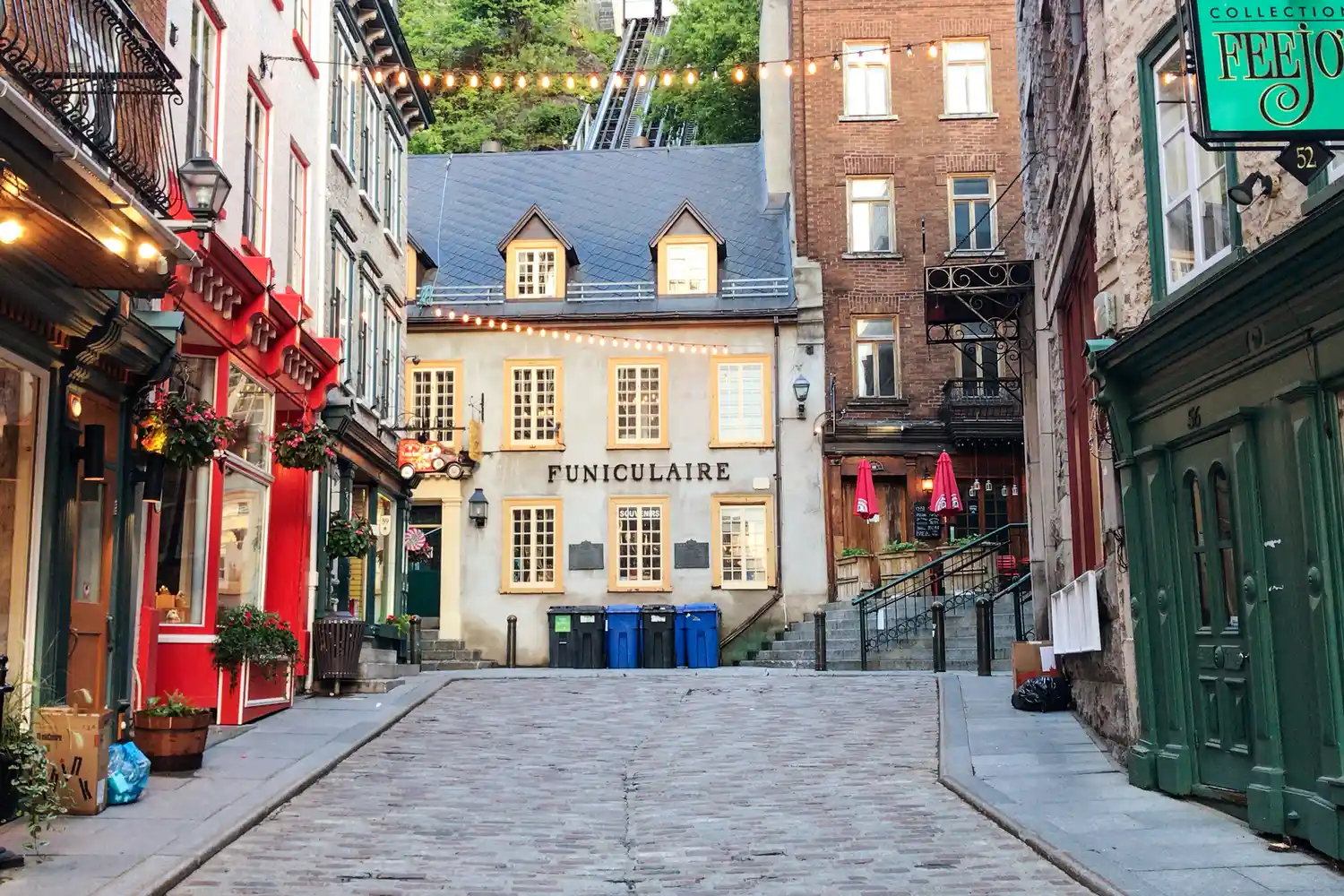 A scenic view of a cobblestone street in Old Quebec City with traditional architecture and the city funicular.