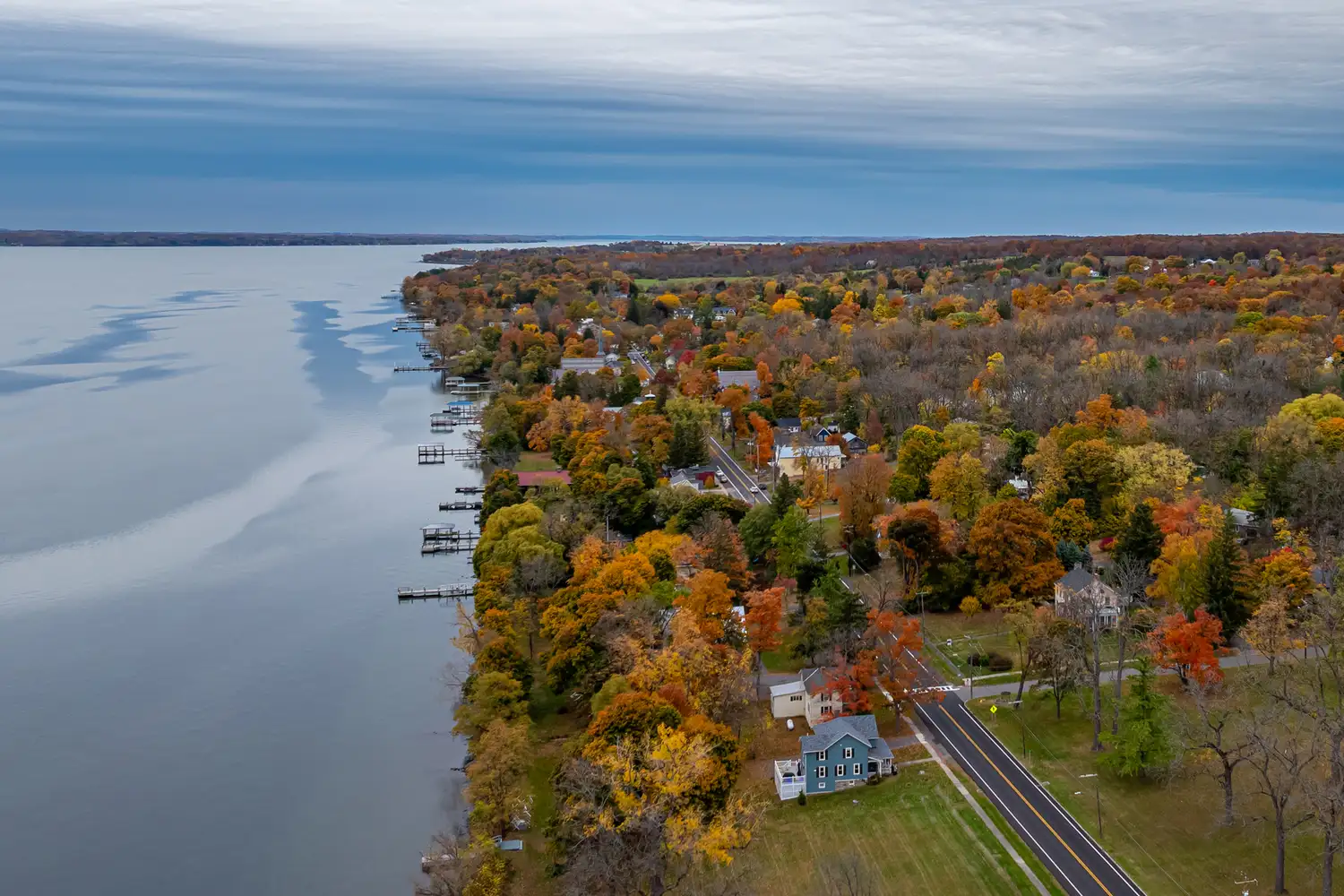An aerial perspective of colorful autumn trees and lakeside homes in Aurora, New York.