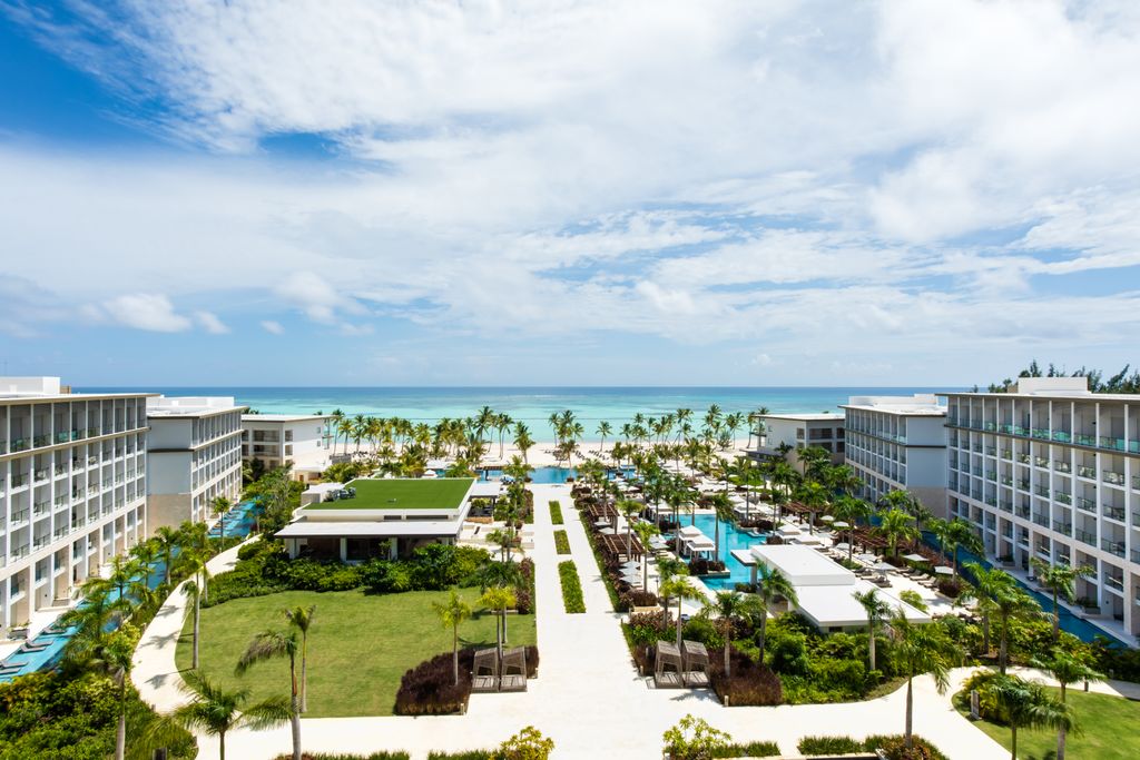 Modern resort buildings and a beachside infinity pool overlooking bright turquoise Caribbean waters.