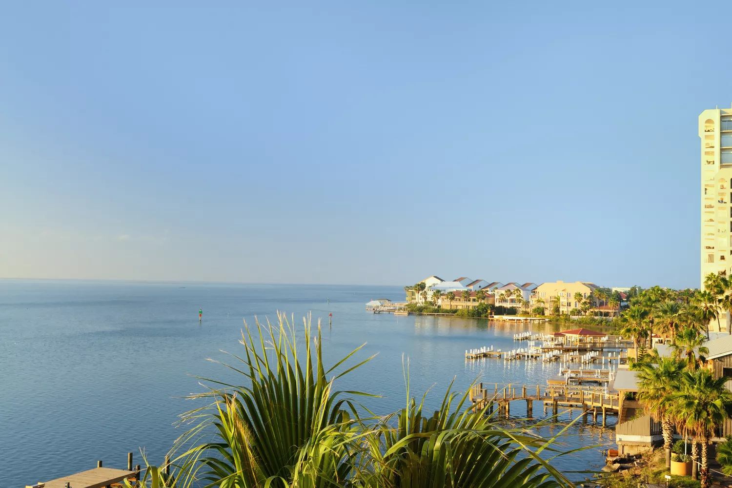 A view of the calm Laguna Madre waters with high-rise beach condos and a marina in the background at South Padre Island.