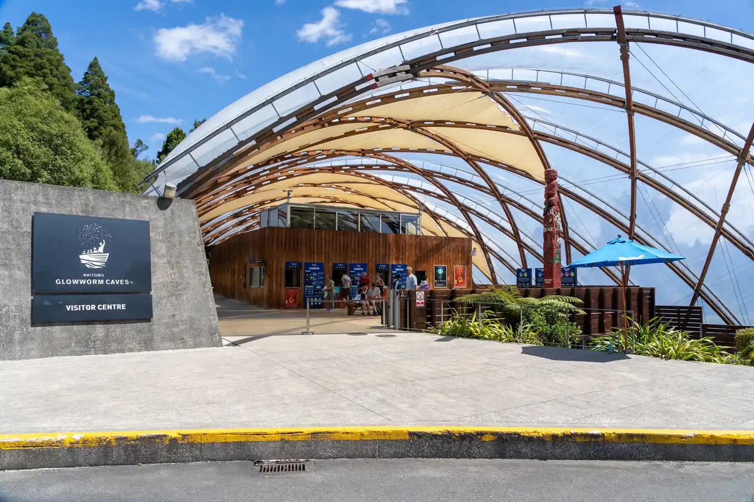 Exterior of the modern Waitomo Glowworm Caves visitor center with its iconic curved roof.