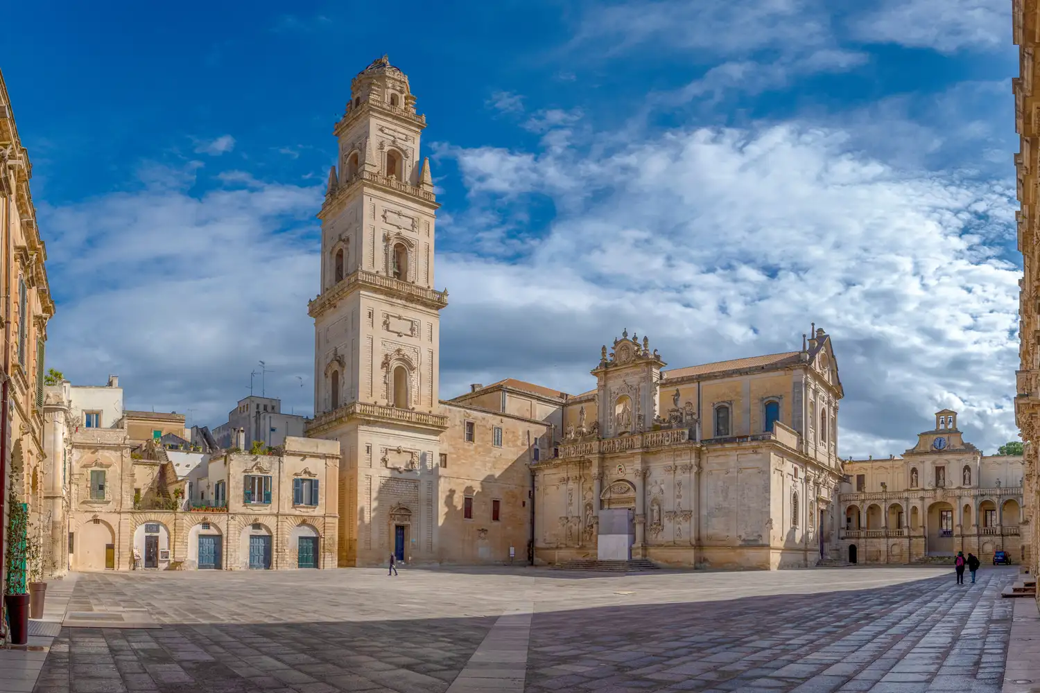 Piazza del Duomo in Lecce featuring honey-colored Baroque buildings and a tall bell tower.