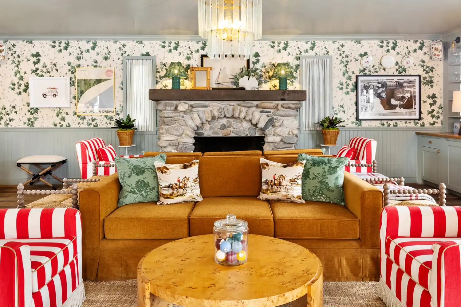 A boutique hotel lounge featuring a stone fireplace, blue velvet chairs, and colorful patterned rugs.
